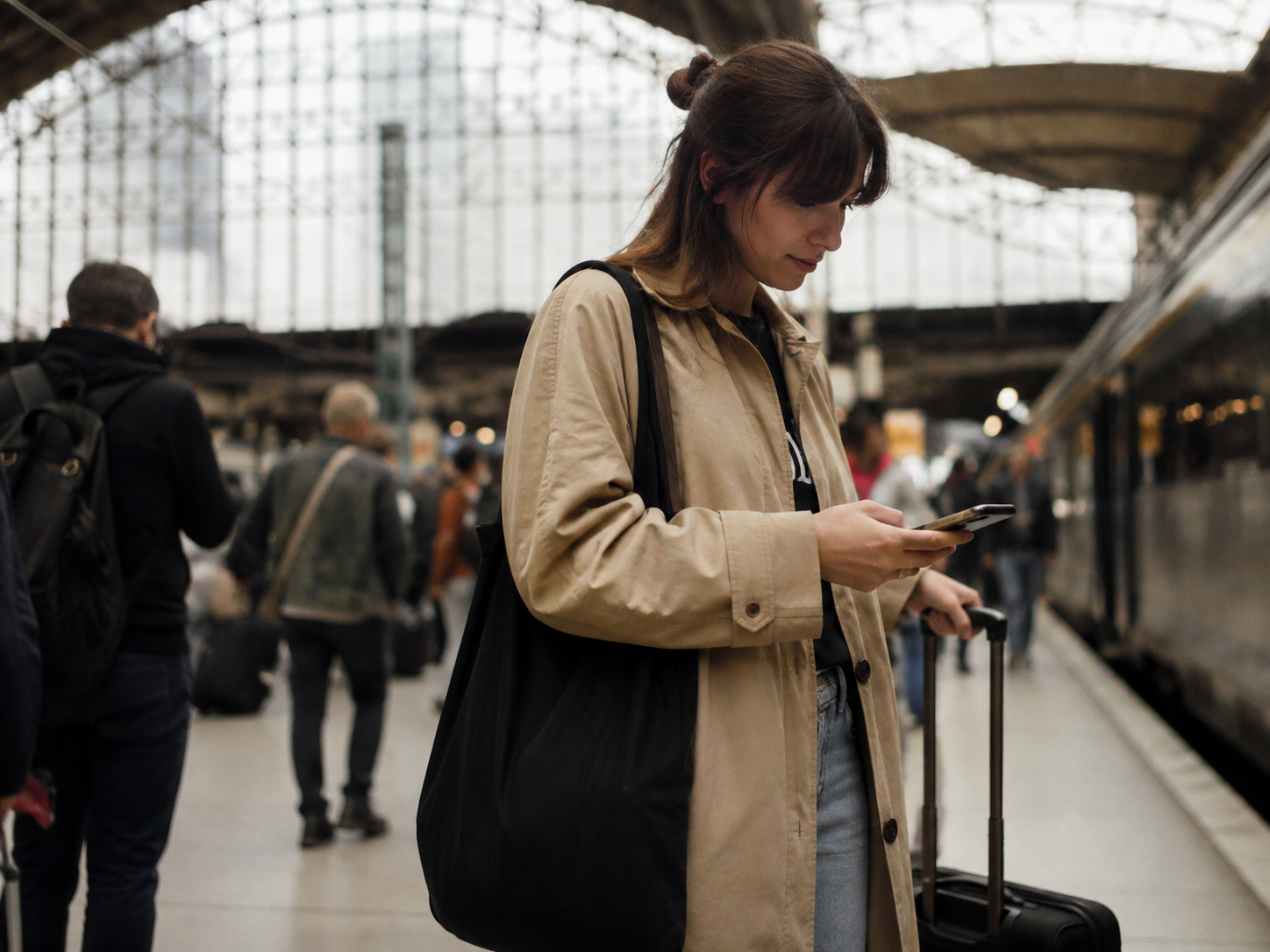 A traveller checking her phone on a train platform